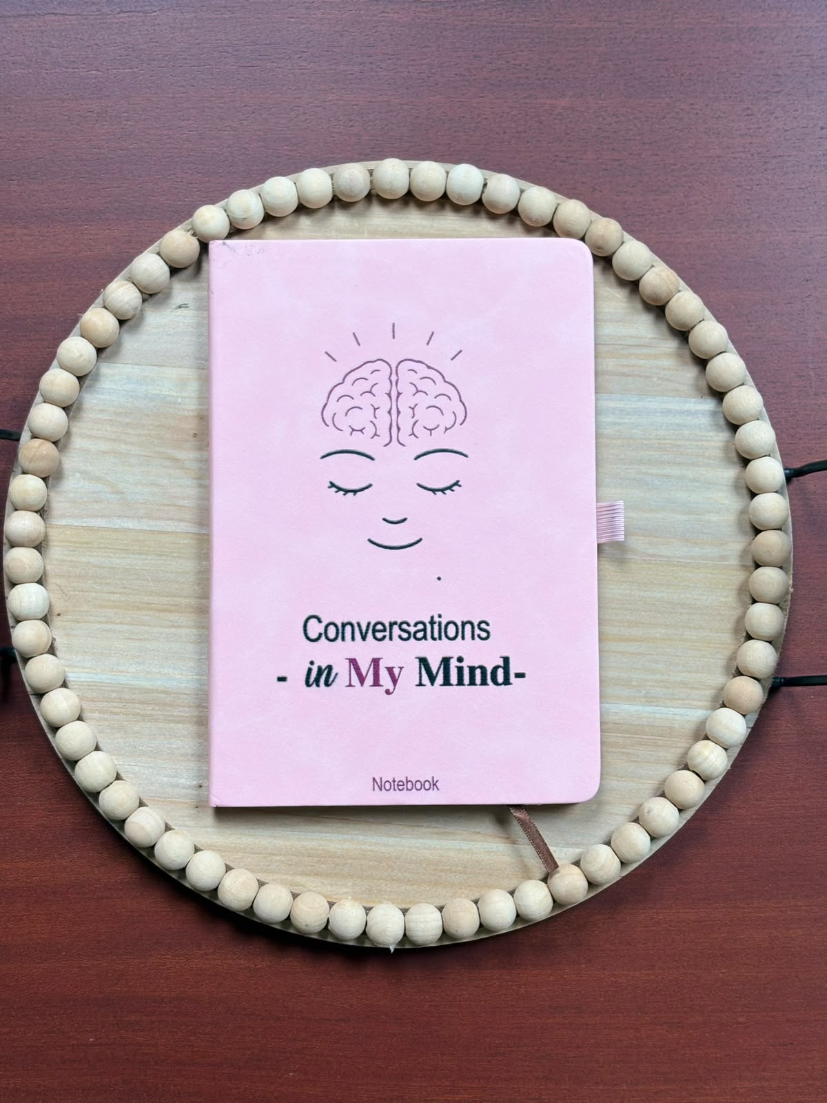 Pink Conversations in My Mind notebook on a wooden beaded tray