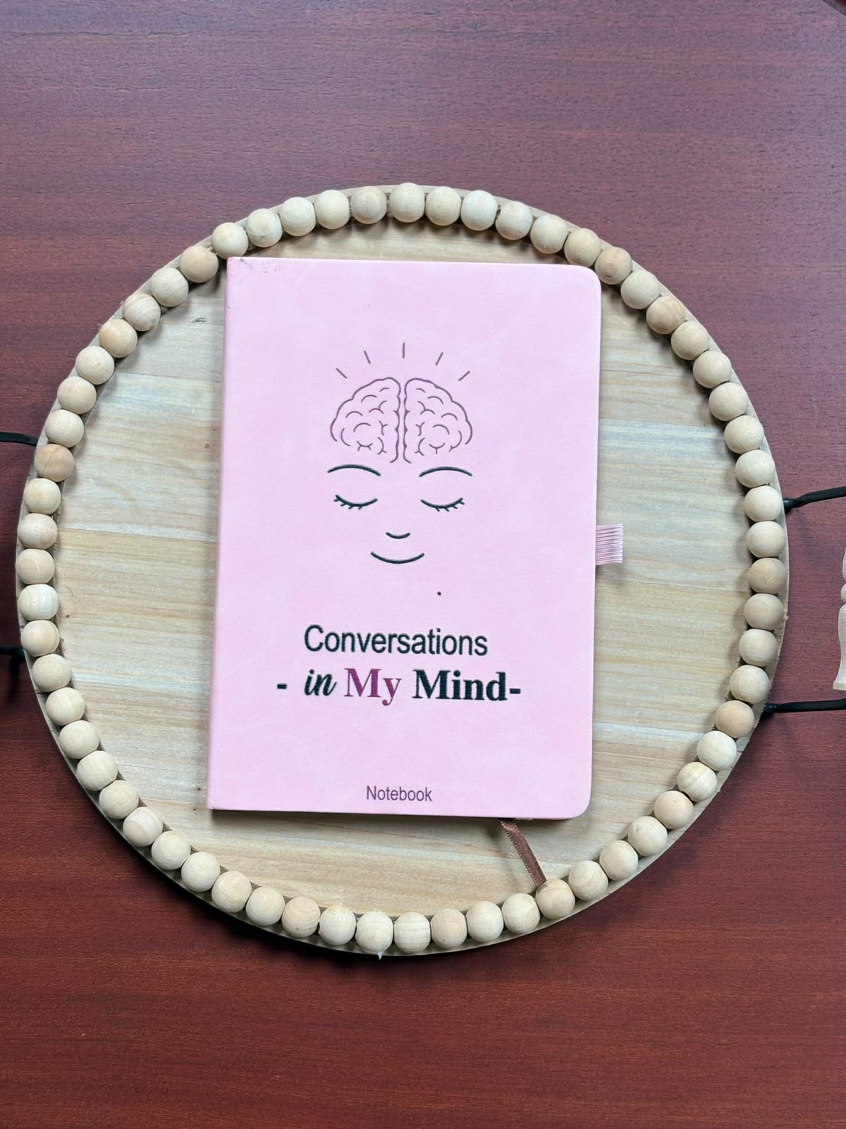 Pink Conversations in My Mind notebook with an illustrated face and brain on the cover